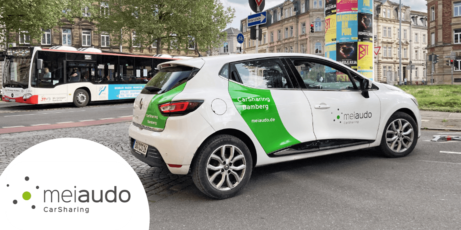 Weiß-grünes Auto und Logo des Carsharing-Partners meiaudo. copyright Ökobil e.V. / meiaudo CarSharing
