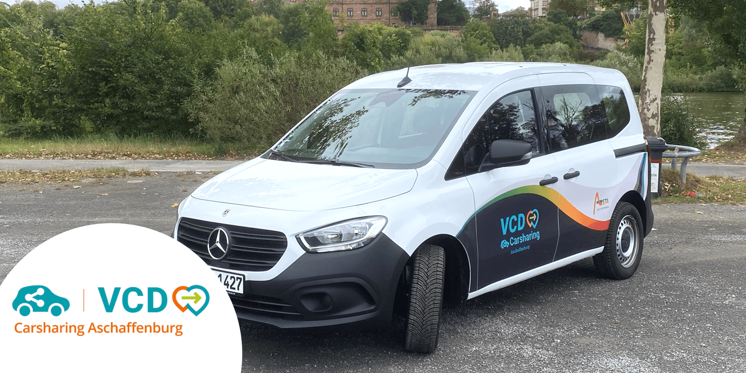 Weißes Mercedes Citan Fahrzeug vom Carsharing Anbieter VCD Aschaffenburg auf Parkplatz vor einem Park und im Hintergrund Bäume, Teich und die Burg von Aschaffenburg. copyright VCD Kreisverband Aschaffenburg-Miltenberg e.V.