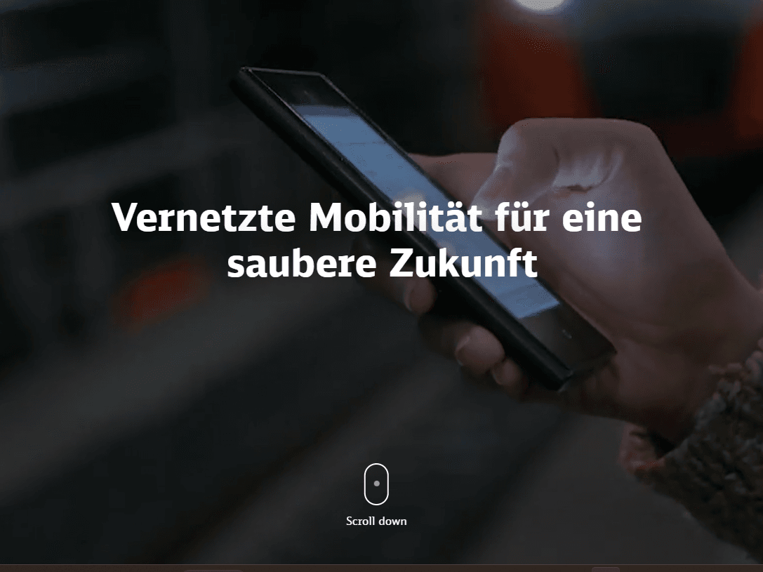 Eine Hand hält ein Smartphone mit dem Text 'Vernetzte Mobilität für eine saubere Zukunft' im Vordergrund.