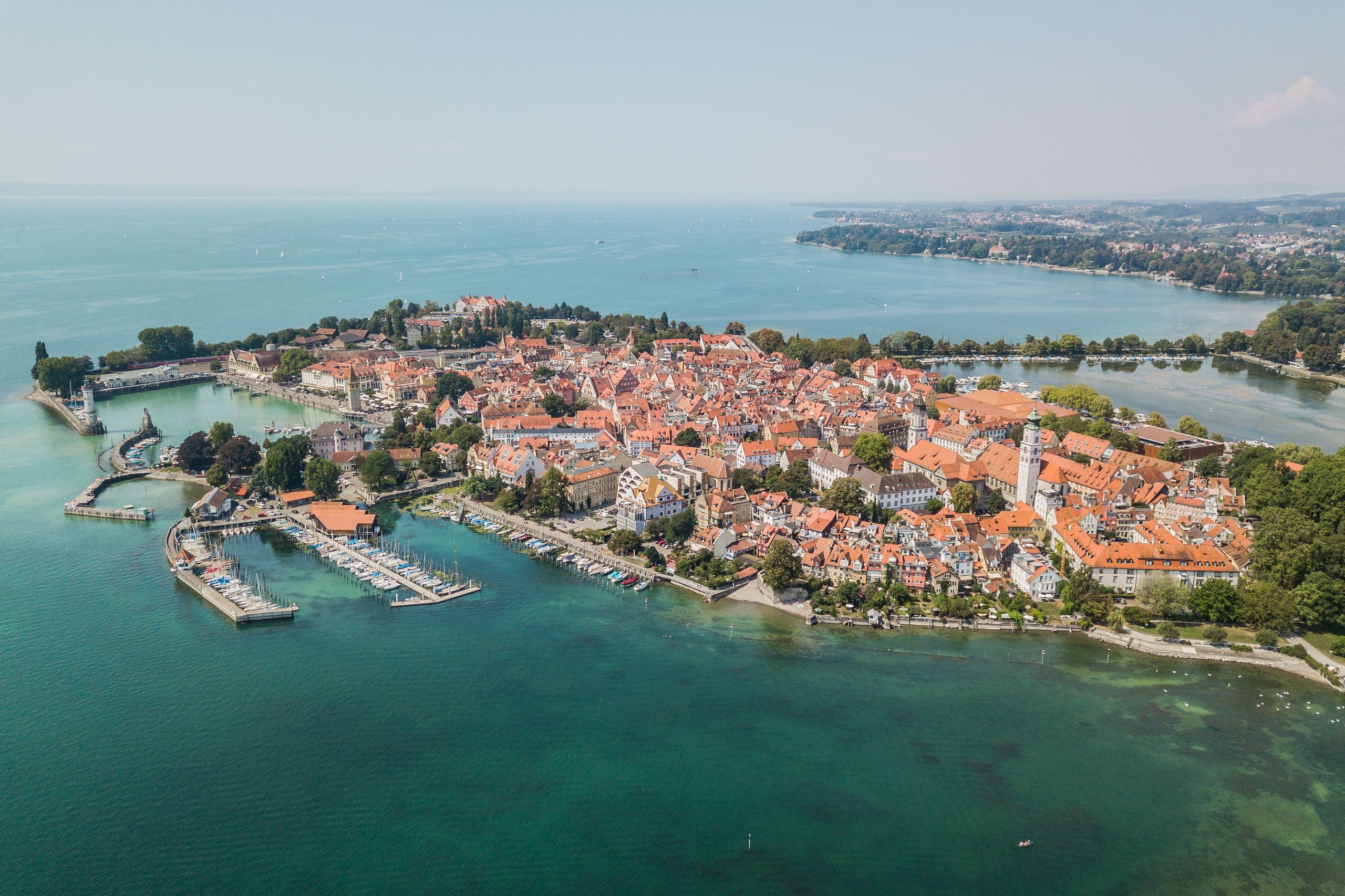 Luftaufnahme einer malerischen Stadt am Bodensee, umgeben von klarem blauen Wasser und grünen Landschaften. copyright Foto: istock.com/Medvedkov